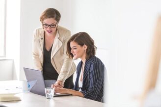 Two business women working on laptops