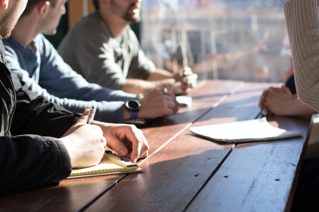 Four men sitting around table talking