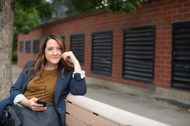 woman sitting on park bench with phone