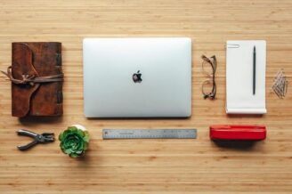 laptop, paper, glasses, ruler and plant on wood desk