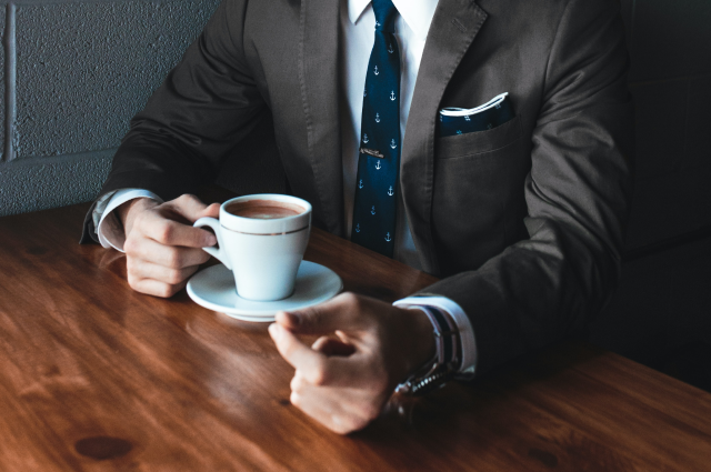 business man in suit drinking coffee at table