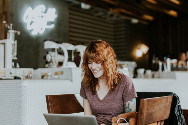 woman sitting and working on laptop in coffee shop