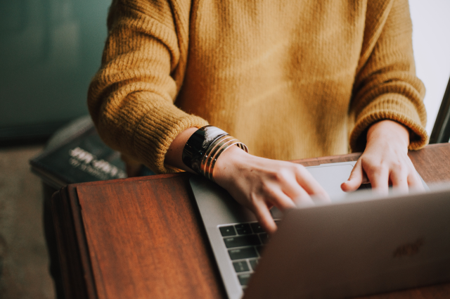 woman with bracelet sitting at desk working on laptop