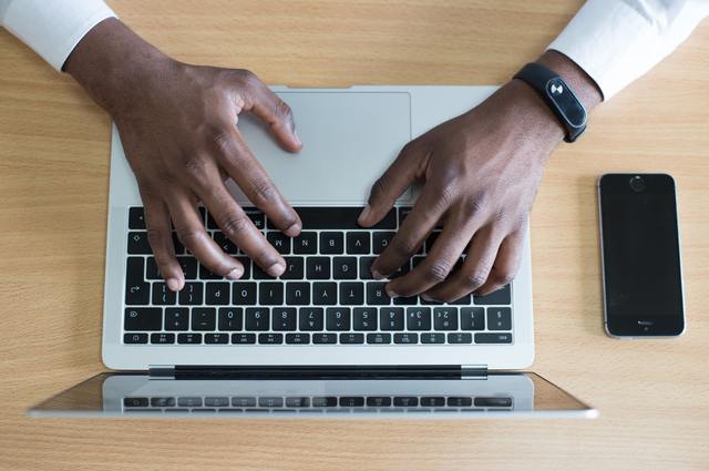 Two hands typing on laptop