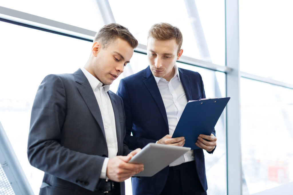 Two businessmen comparing sales pipelines and sales funnels on clipboards