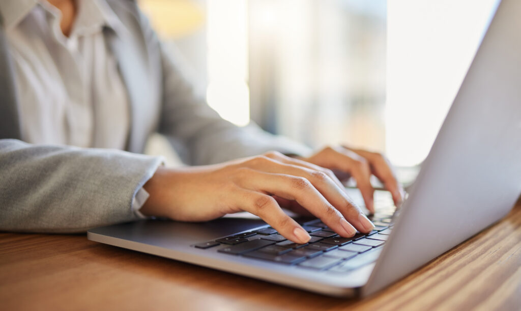 woman's hands typing on laptop working with an AI marketing tool