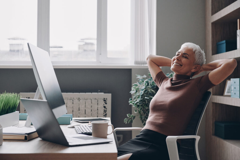 Happy business woman sitting at her desk leaning back smiling showing the concept of AI for sales