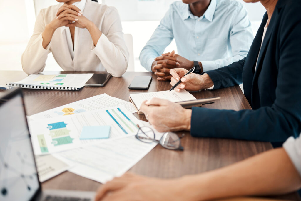 Group of businesspeople sitting around a conference table reviewing printed revenue marketing reports