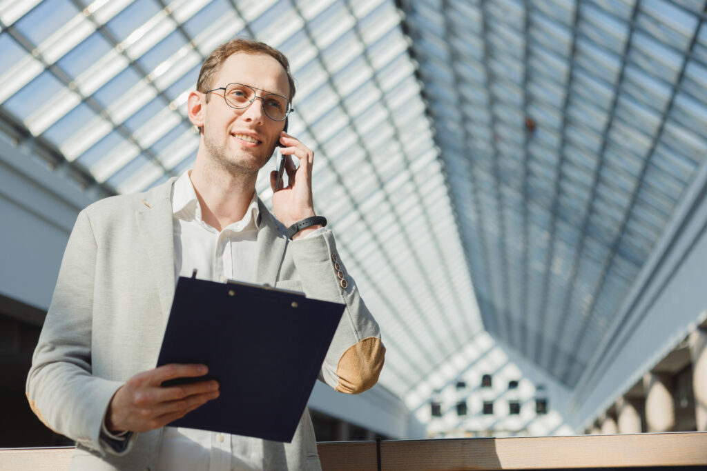 Businessman stands on the phone holding a clipboard talking about sales intelligence data