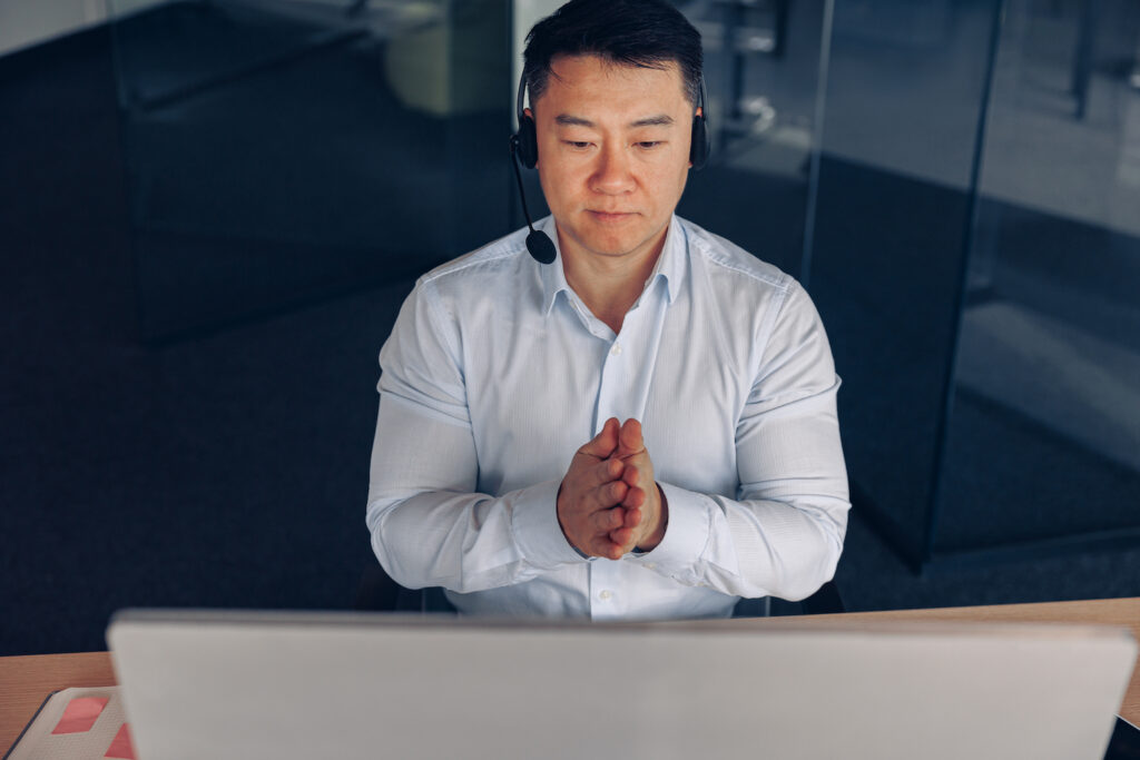 Sales rep sits in front of computer monitor with headset on getting ready to send some sales emails