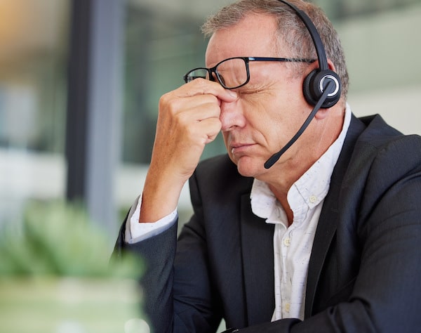 Businessman sitting at a desk pinching his nose in frustration symbolizing common mistakes in outbound sales strategies