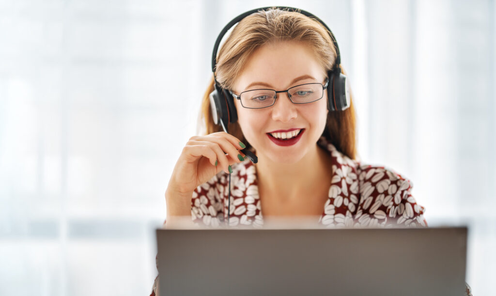 Sales rep wearing a headset sits in front of laptop talking on the phone, representing social listening