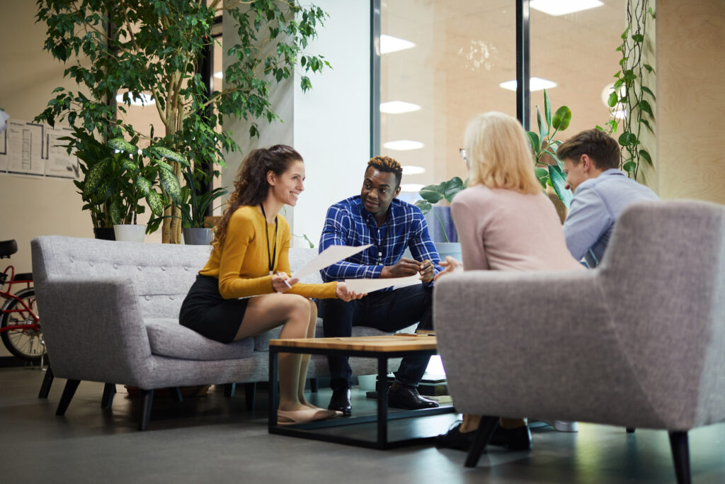 Team of sales reps sit together on couches for a social listening training