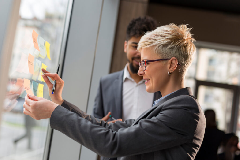 Two marketers stand in front of whiteboard brainstorming ideas for their brand value proposition