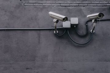 photo of surveillance cameras on wall of building, symbolizing cybersecurity concept
