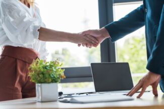 Two business professionals standing over a desk shaking hands, symbolizing ABM strategy