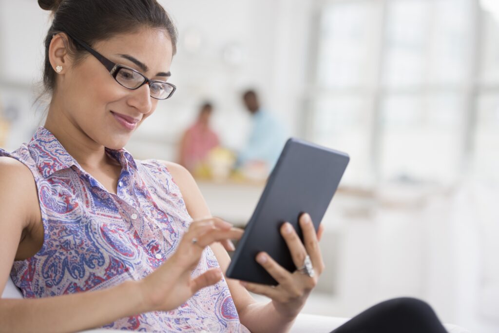 Businesswoman sits in chair reading some ABM program content on her tablet