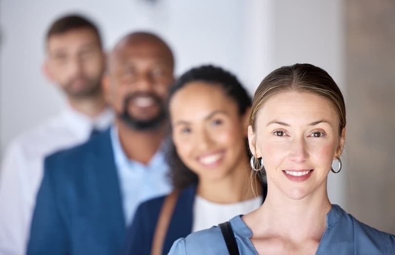 Four business professionals stand in line looking at the camera representing an account-based marketing for B2B team