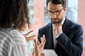 A man and woman sales leader stand facing each other discussing B2B sales during a recession