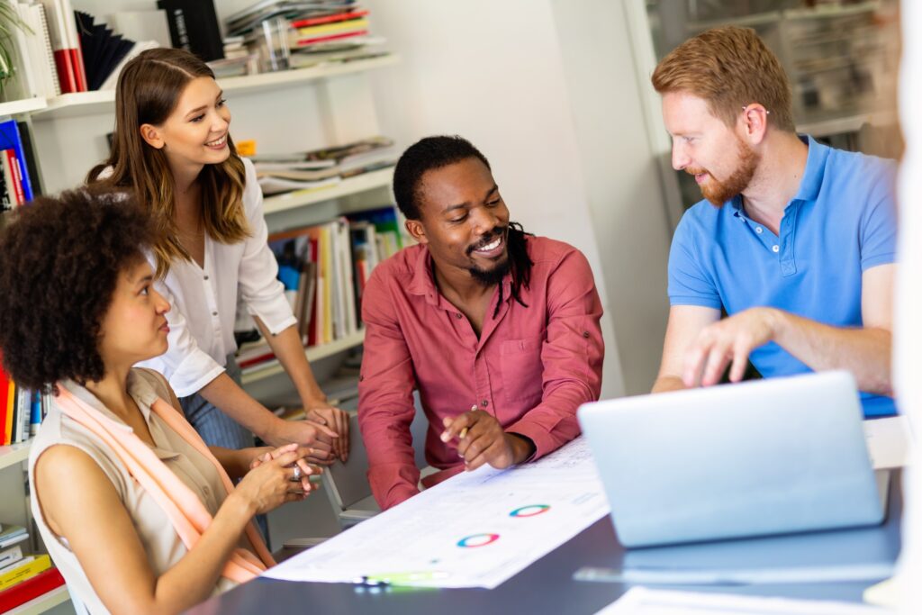 Four diverse sales and marketing professionals sit together at a conference table looking at B2B sales numbers from LeadLander's mobile app