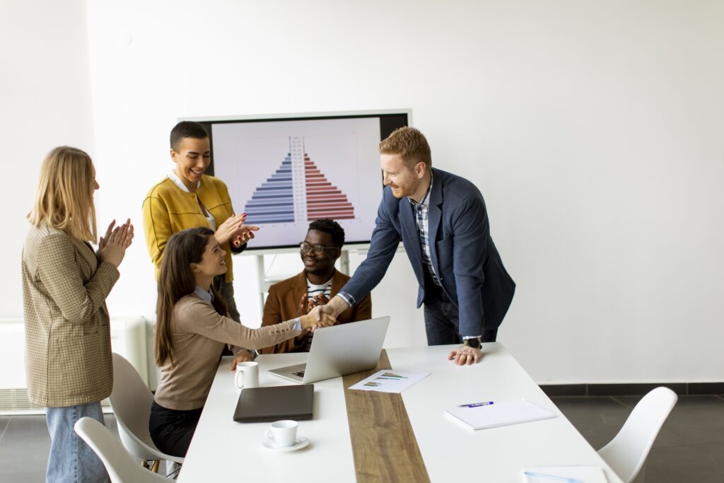 Sales and marketing team stand around a conference table congratulating a colleague on her work with behavioral data and sales