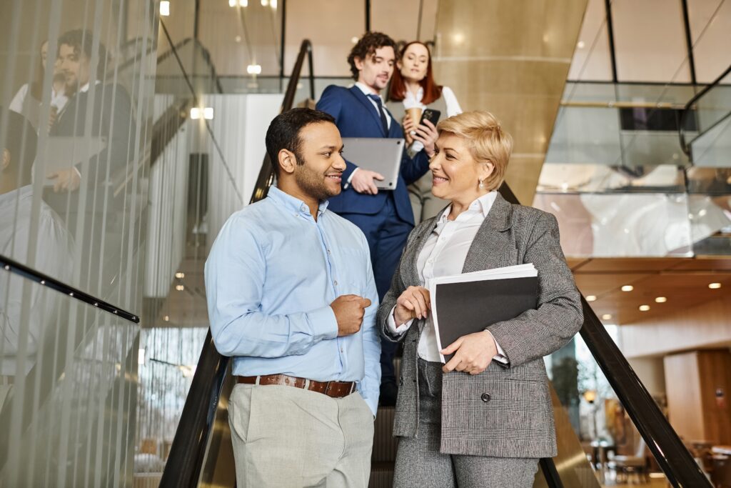 A group of professionals stands on an escalator talking to each other in pairs about LinkedIn AI