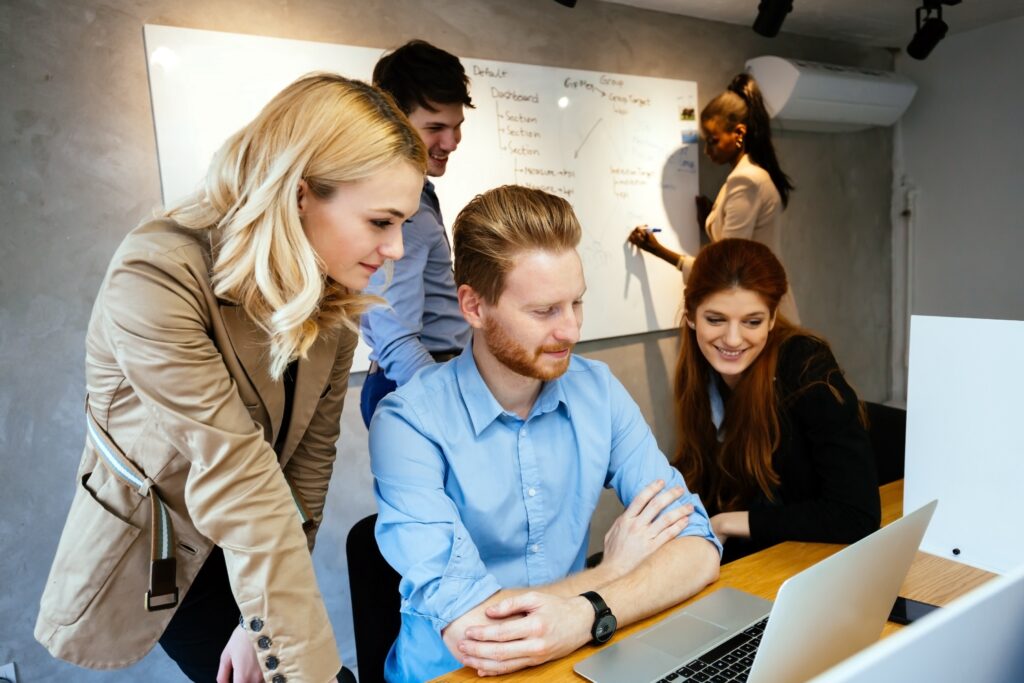 Group of marketing professionals stand and sit around a desk reviewing website analytics mapped to the B2B buyer's journey