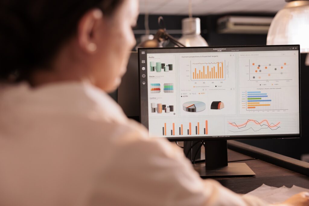 Back of businesswoman facing a computer screen showing analytics that represent metrics for the B2B sales cycle