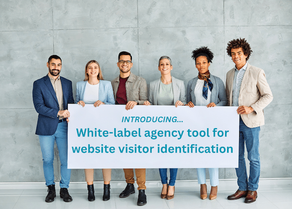 Group of businesspeople stand together looking at the camera, holding a sign about LeadLander's new white-label agency tool for website visitor identification