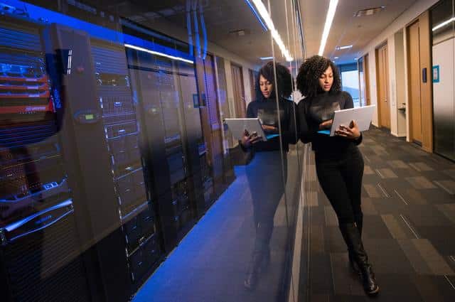 business woman leaning on wall working on laptop